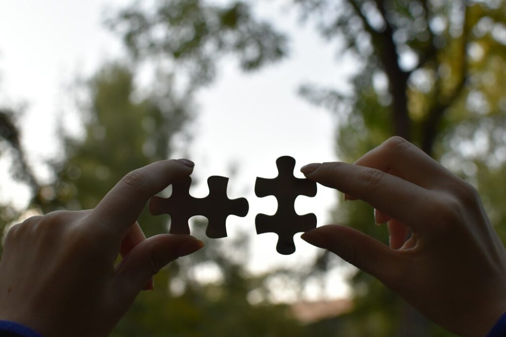Two hands bringing puzzle pieces together, representing collaborative business relationships under ISO 44001