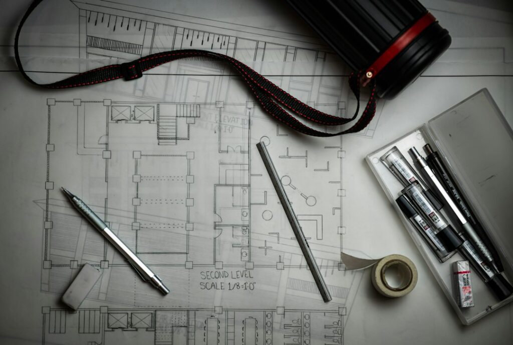 Engineering blueprints with drafting pencils and a ruler, representing building an AS9100 quality system from scratch in a start-up