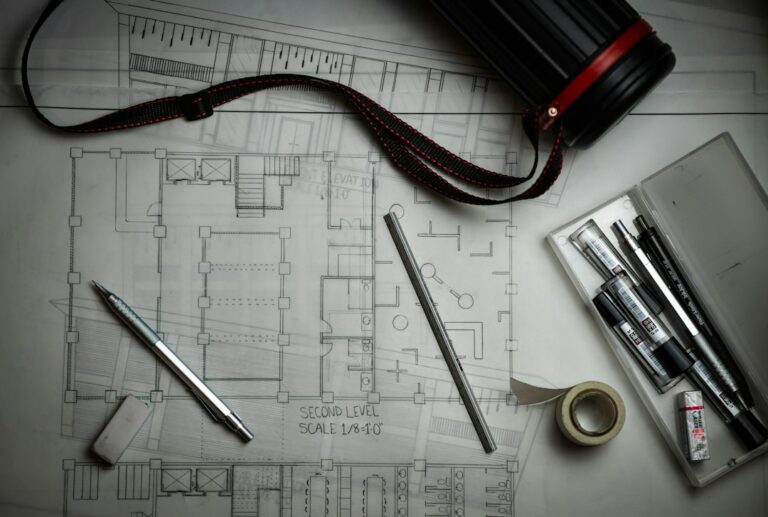 Engineering blueprints with drafting pencils and a ruler, representing building an AS9100 quality system from scratch in a start-up